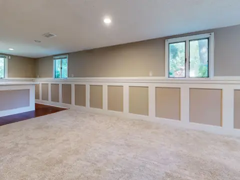 A bright finished basement with daylight windows and a carpeted floor