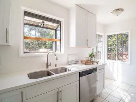 A bright white kitchen with a steel sink and a dishwasher