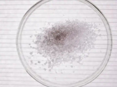 White crystals in a glass dish on lined paper