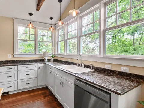 A bright white kitchen with a long row of windows over the sink