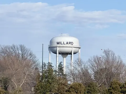 The white Millard water tower above bare trees in southwest Omaha