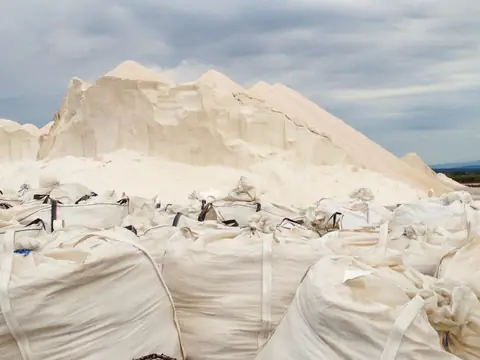 Large white bags of salt stacked in front of a salt pile