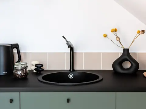 A black round sink and a black faucet on a dark counter