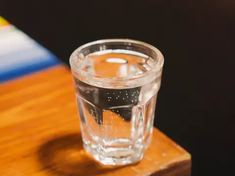 A glass of water on the edge of a wooden table