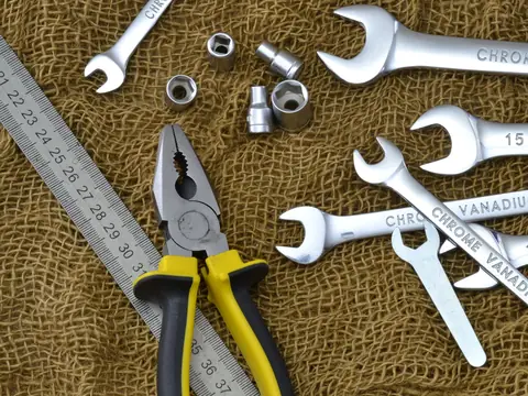 Wrenches, pliers, sockets and a ruler laid out on burlap