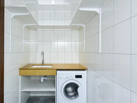 A white tiled utility corner with a small sink and a washing machine