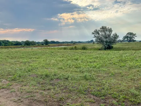 Open grassland and trees by an oxbow of the Elkhorn River in Nebraska under a bright sky