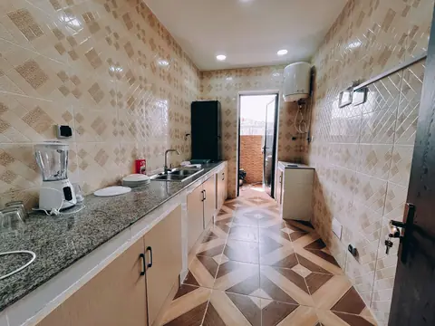 A long tiled kitchen with a water heater on the far wall