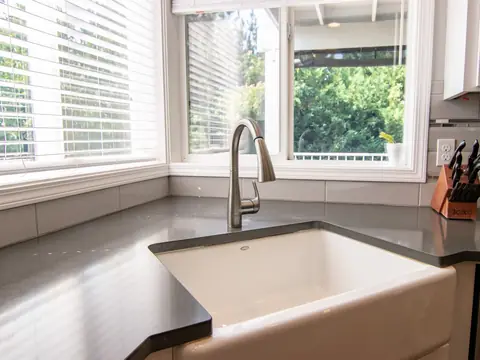 A kitchen sink with a steel faucet by a bright window